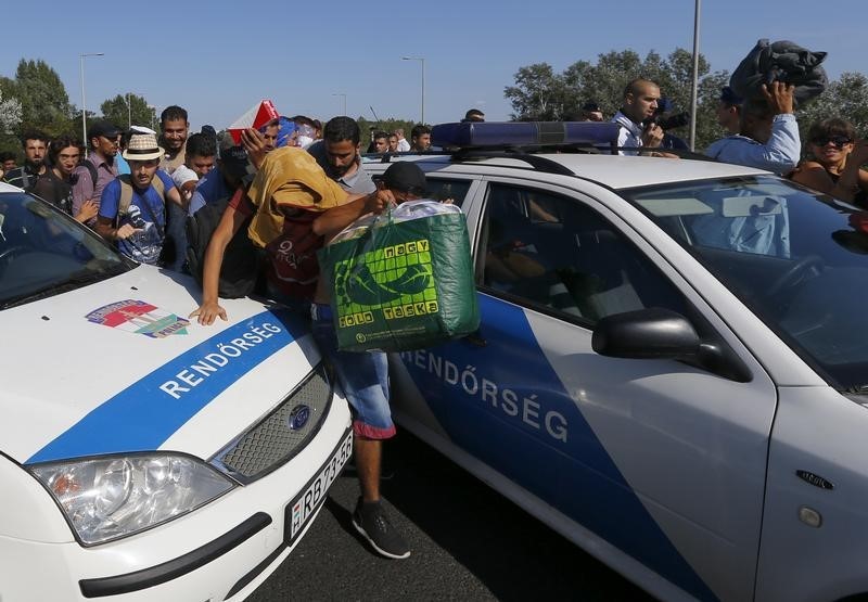 © Reuters. مهاجرون يقتحمون حاجزا للشرطة على طريق سريع في المجر