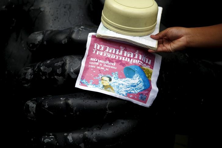 © Reuters. An opposition student pours water over a copy of the military-backed draft constitution during a protest against it in Bangkok