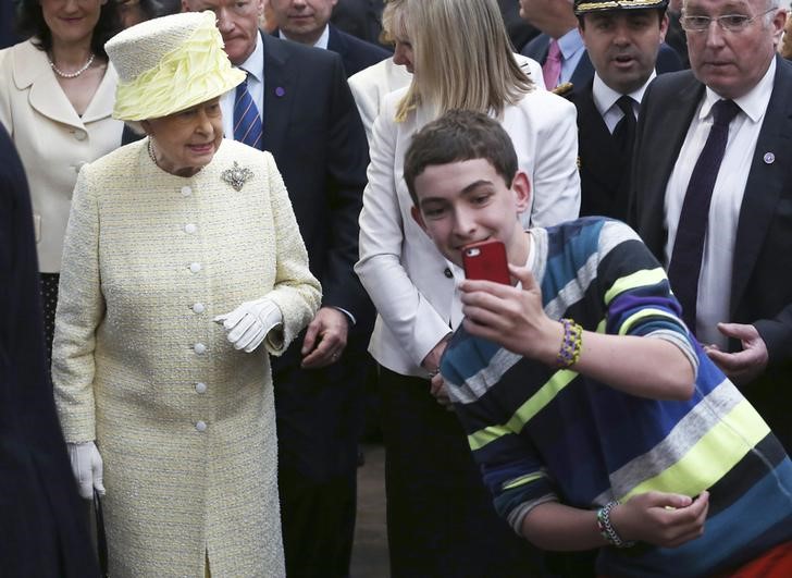 © Reuters. A local youth takes a selfie in front of Britain's Queen Elizabeth in St George's indoor market in Belfast