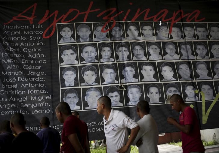 © Reuters. Newly enrolled students stand near a banner showing the photographs of the 43 missing students of the Ayotzinapa teachers' training college, at the college in Tixtla