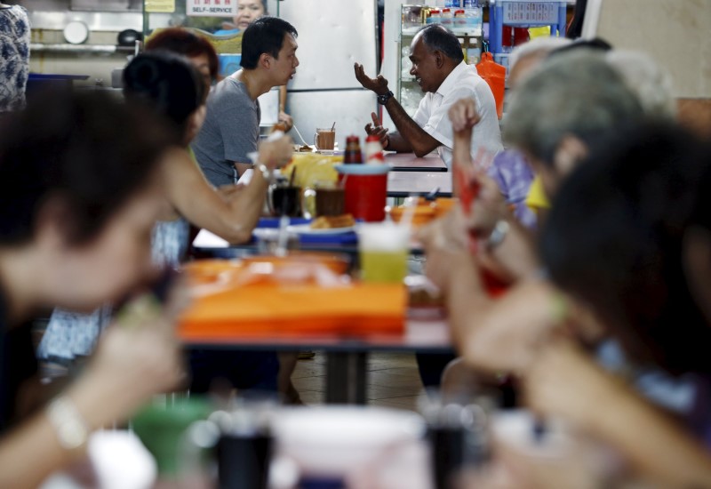 © Reuters. Singapore's Foreign Minister K. Shanmugam of the ruling People's Action Party speaks with residents during a visit to a hawker centre in Singapore 