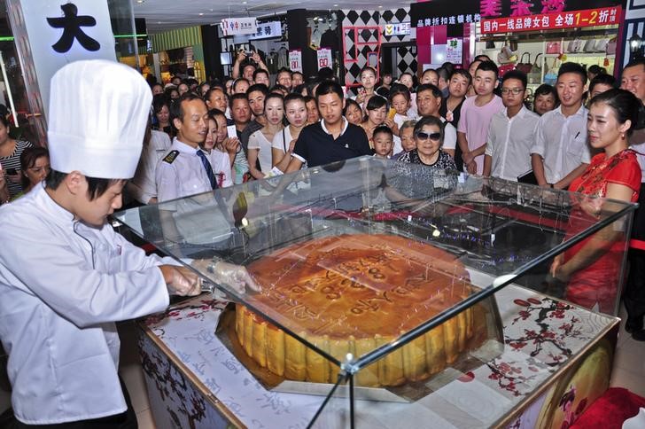 © Reuters. A baker cuts a mooncake measuring one metre in diameter, before distributing it for free to customers at a shopping mall in Wuhan