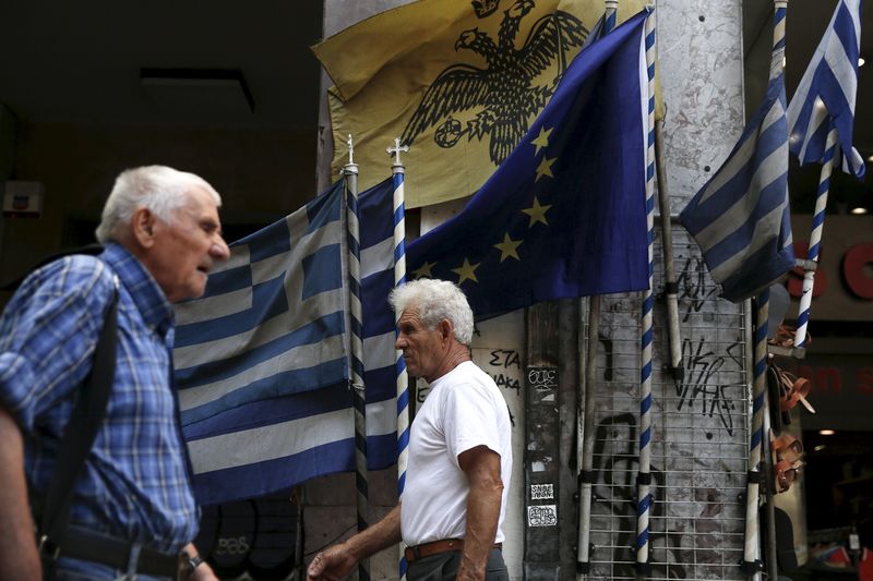 © Reuters. People make their way next to Greek national flags and a European Union flag in Athens
