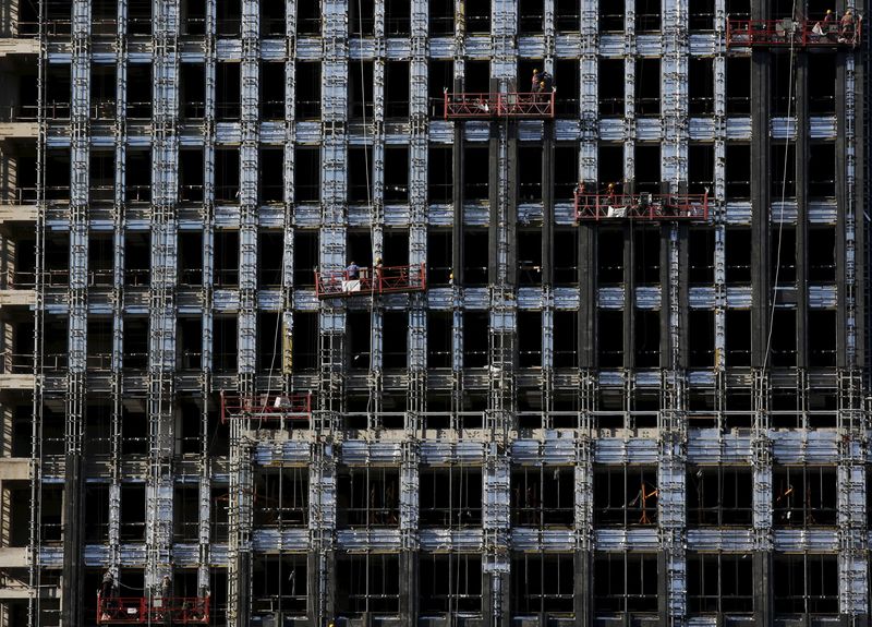 © Reuters. File photo of labourers on lifts working on a new residential complex under construction in Beijing