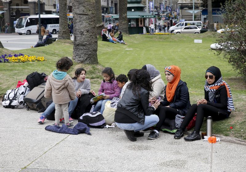 © Reuters. Membros das cinco famílias de refugiados sírios asilados no Uruguai protestam na praça da Independência em Montevidéu