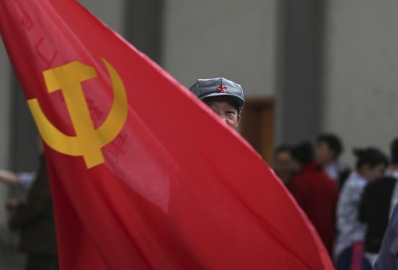 © Reuters. A participant waves a Chinese Communist Party flag as he waits backstage before his performance at a line dancing competition in Kunming