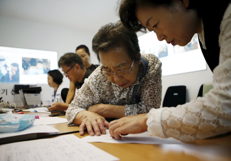 © Reuters. A woman who said she has family members living in North Korea gets help to prepare documents for reunion at the Red Cross building in Seoul