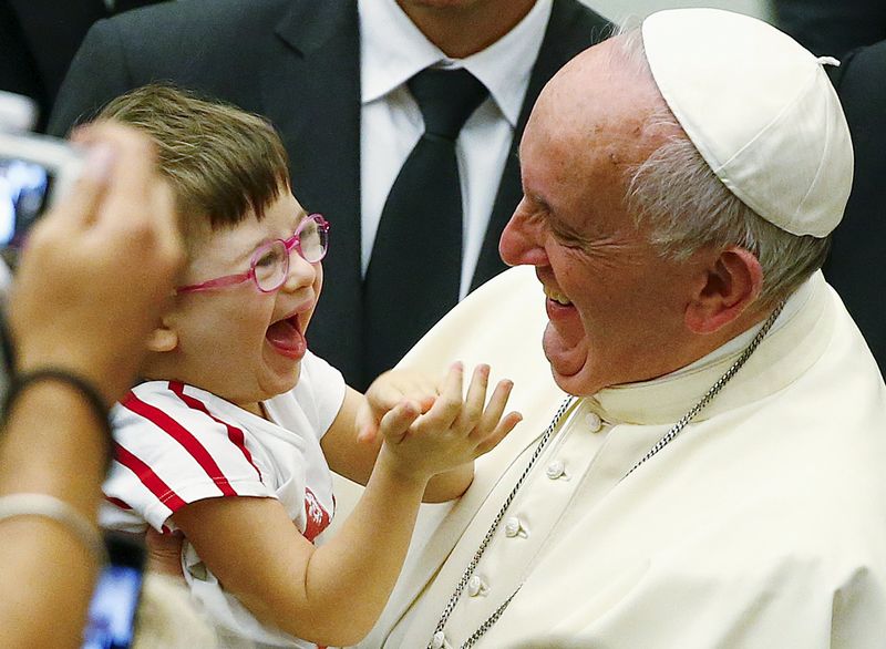 © Reuters. Papa Francisco com criança no colo no Vaticano