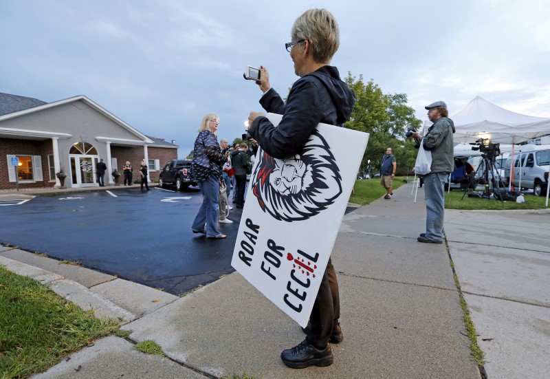 © Reuters. Protester takes photo of the River Bluff Dental clinic after American hunter Walter Palmer arrives in Bloomington