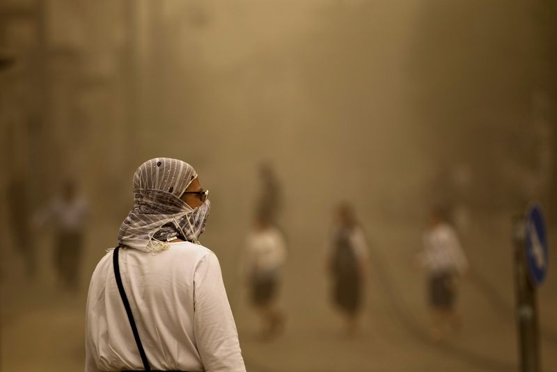 © Reuters. Pedestre caminha com o rosto coberto em meio a tempestade de areia em Jerusalém