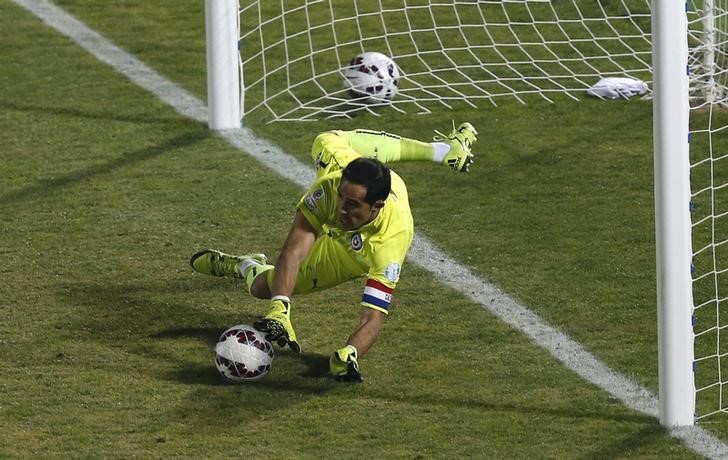 © Reuters. Goleiro Claudio Bravo, da seleção do Chile, defende pênalti cobrado pelo argentino Ever Banega na final da Copa América em Santiago