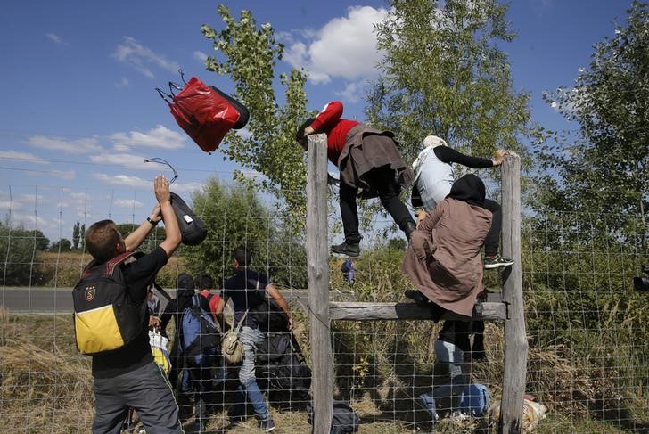 © Reuters. Imigrantes pulando cerca de proteção em Roszke, na Hungria