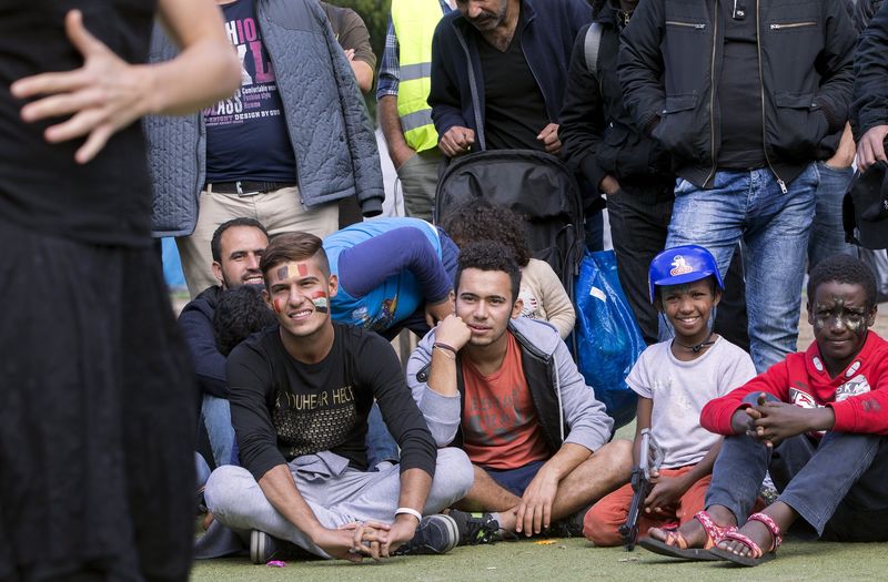 © Reuters. Migrants watch a show presented by a troupe of artists at a makeshift camp outside the foreign office in Brussels, Belgium