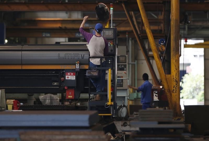 © Reuters. Men work around metal procession machines at a factory in Urayasu