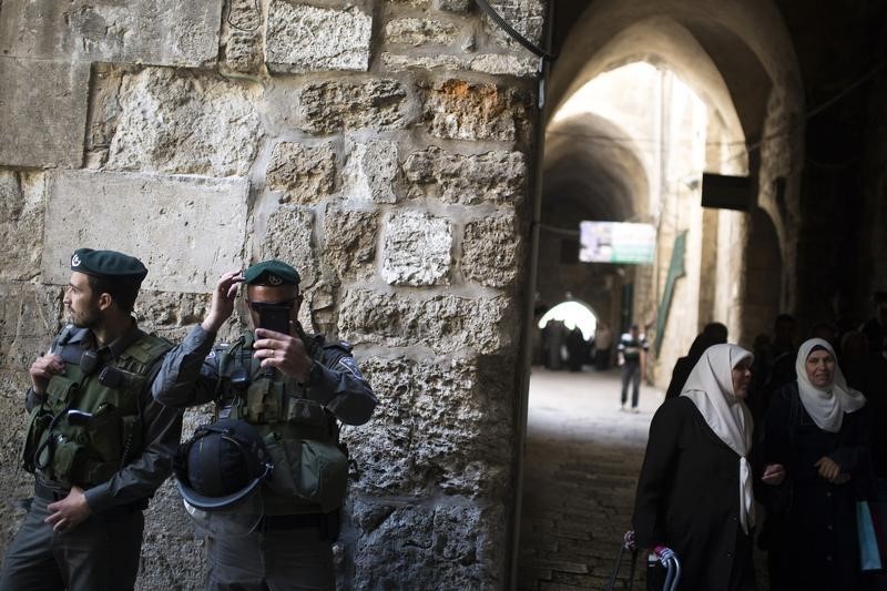 © Reuters. Palestinian women walk near Israeli border policemen after Friday prayers in Jerusalem's Old City