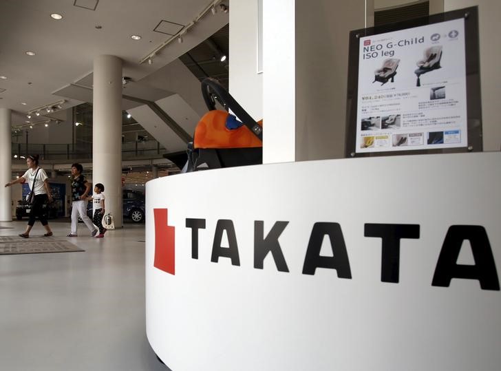 © Reuters. Visitors walk behind a logo of Takata Corp on its display at a showroom for vehicles in Tokyo