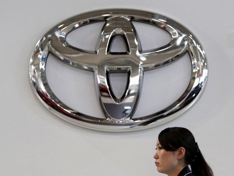 © Reuters. A woman walks under a logo of Toyota Motor Corp at the company's showroom in Tokyo