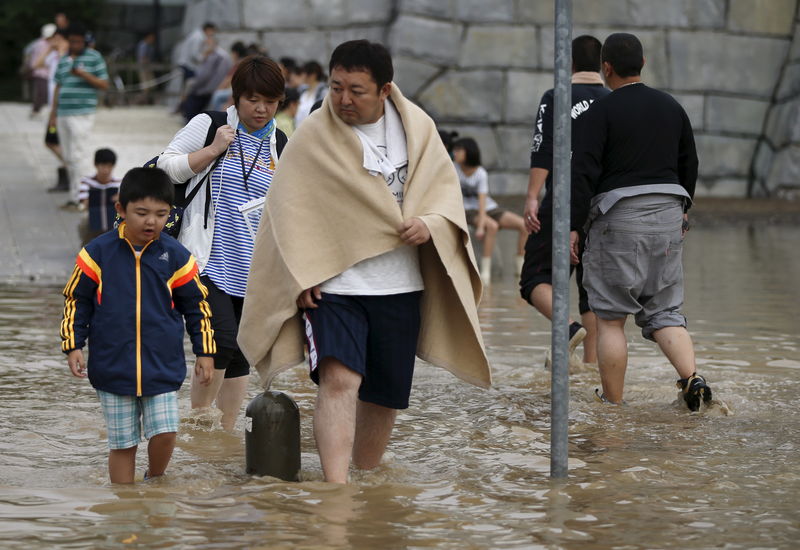 © Reuters. Local residents wade through a residential area flooded by the Kinugawa river, caused by typhoon Etau, in Joso