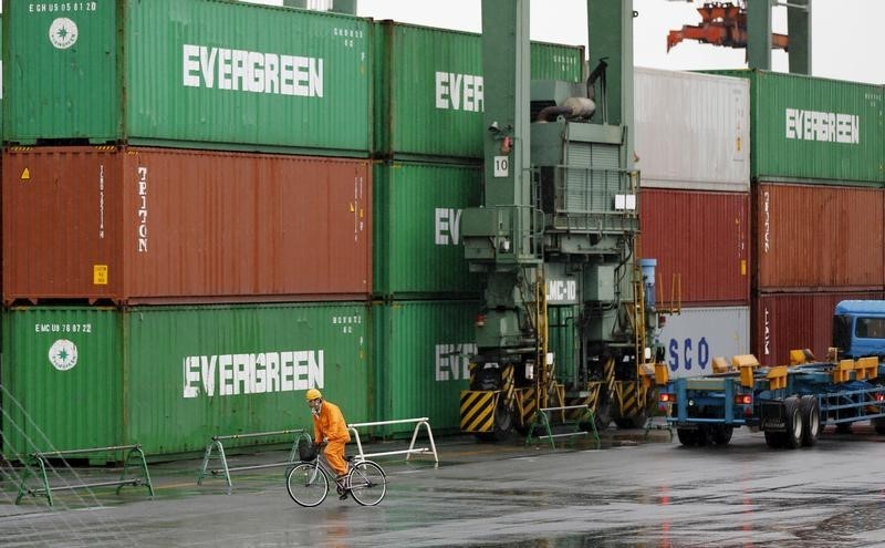 © Reuters. A worker rides a bicycle in a container area at a port in Tokyo