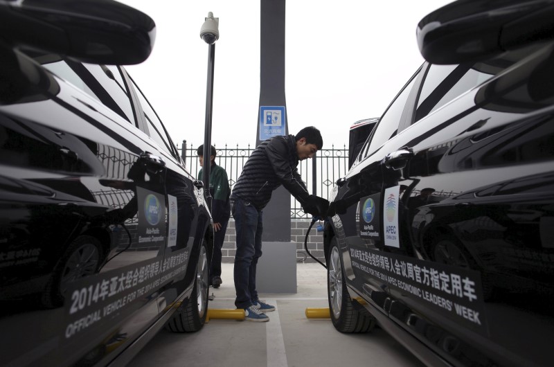 © Reuters. File photo of a man charging the batteries of BAIC Motors electric cars in Beijing