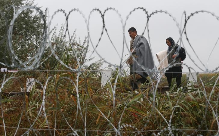 © Reuters. Imigrantes atrás de cerca com arame farpado em Roszke, na Hungria