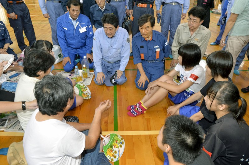 © Reuters. Japan's PM Abe talks with evacuees from an area flooded by the Kinugawa river, caused by typhoon Etau, at an evacuation center in Joso