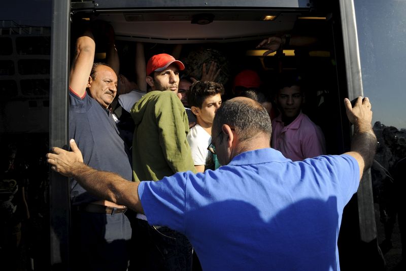 © Reuters. Syrian refugees and migrants board a bus after arriving to the port of Piraeus near Athens 