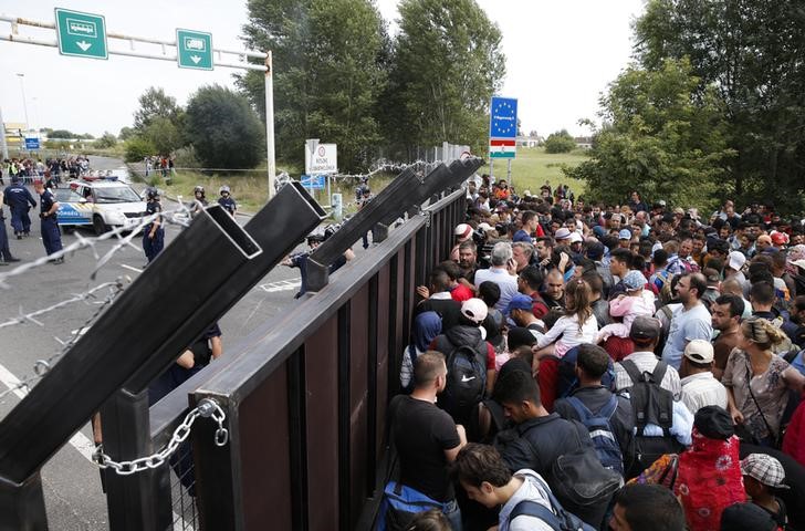 © Reuters. Imigrantes em frente portão na fronteira entre Hungria e Sérvia, no vilarejo de Horgos