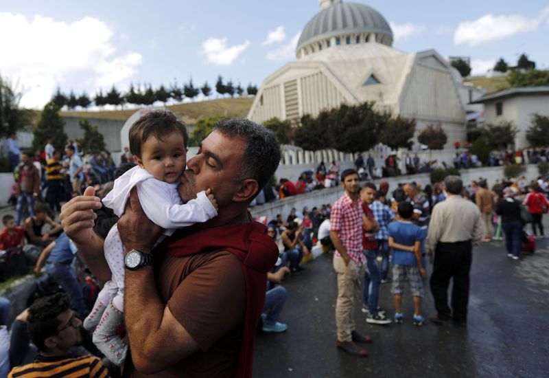 © Reuters. Syrian Kurd Salah ad-Din kisses his 7-month-old daughter Hiro Belo as they wait at the main bus station in Istanbul