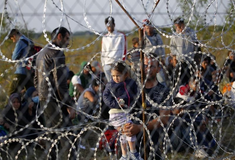 © Reuters. A migrant holds a child as they wait on the Serbian side of the border with Hungary in Asotthalom