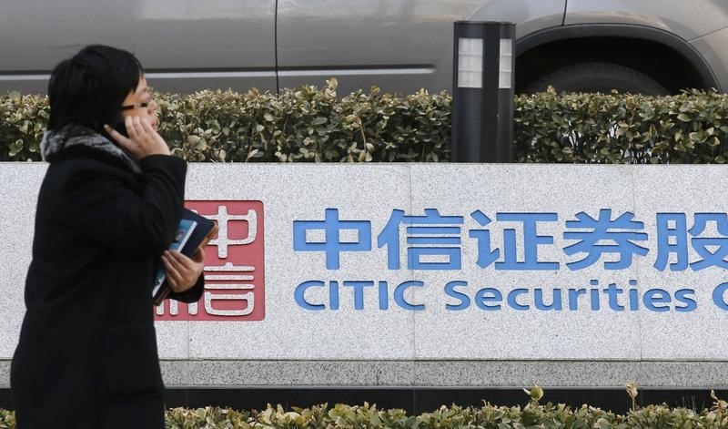 © Reuters. A woman walks past a signboard of CITIC Securities at its head office in Beijing
