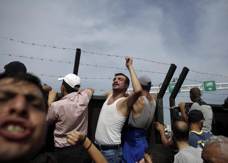 © Reuters. Imigrantes em frente cerca em Horgos, na Sérvia, na fronteira com Hungria