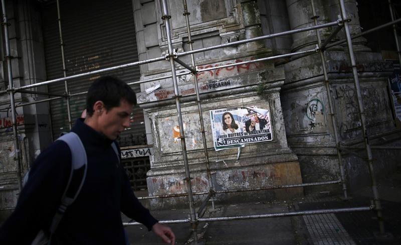 © Reuters. A man walks past a poster with pictures of Argentina's President Fernandez de Kirchner and U.S. for the Southern District of New York Judge Griesa, depicted as Uncle Sam, near the Argentine Congress in Buenos Aires