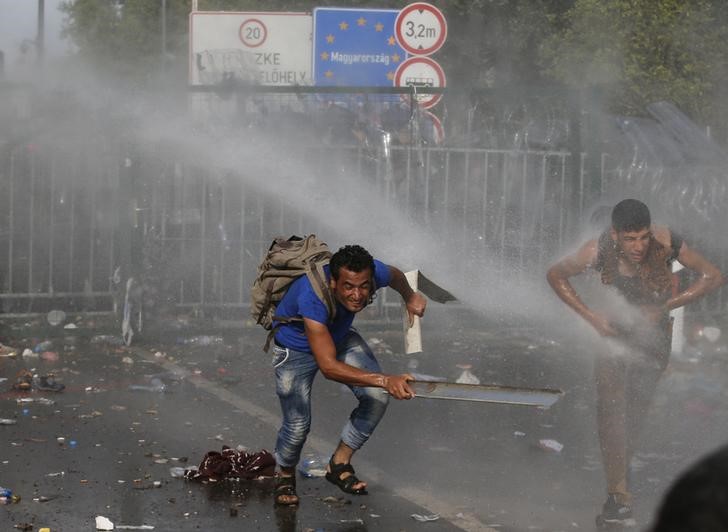 © Reuters. Polícia húngara joga água em imigrantes do lado sérvio da fronteira, perto de Roszke