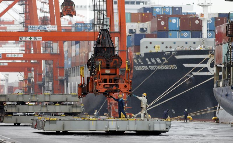 © Reuters. Workers are seen in a container area at a port in Tokyo 