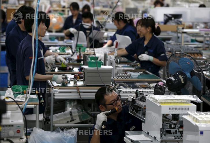 © Reuters. Employees work an assembly line at a factory of Glory Ltd., a manufacturer of automatic change dispensers, in Kazo, north of Tokyo