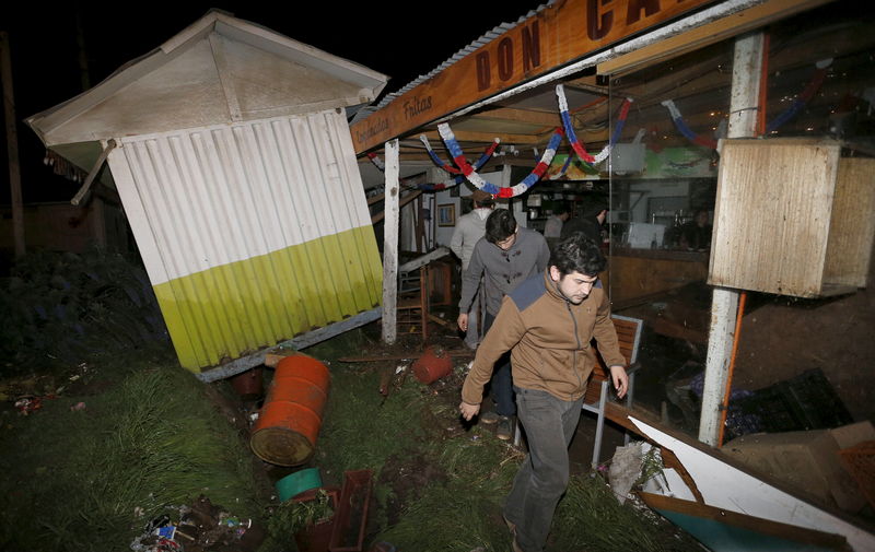 © Reuters. Gente recobra enseres de una tienda destruida por las olas en el balneario de Concón en Chile, tras un terremoto en la zona central.