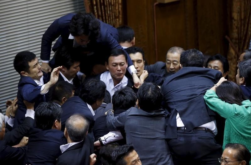 © Reuters. Opposition Democratic Party of Japan lawmaker Konishi climbs over other lawmakers who are guarding Konoike, chairman of the upper house special committee on security, at the parliament in Tokyo