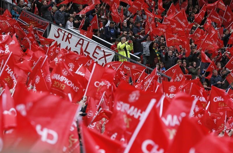 © Reuters. Manchester United fans wave flags before the English Premier League soccer match against Swansea City at Old Trafford stadium in Manchester
