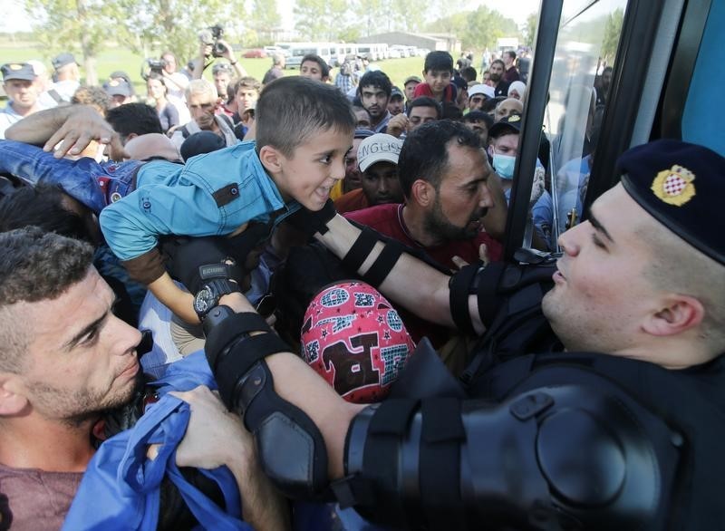 © Reuters. Migranti cercano di salire su un bus a Tovarnik in Croazia 