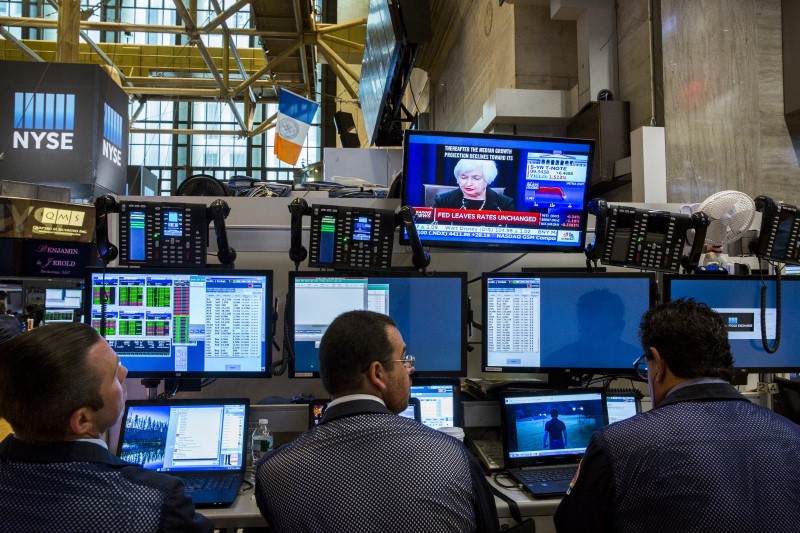 © Reuters. Traders work underneath a television screen showing Federal Reserve Chair Janet Yellen announcing that the Federal Reserve will leave interest rates unchanged on the floor of the New York Stock Exchange in New York 