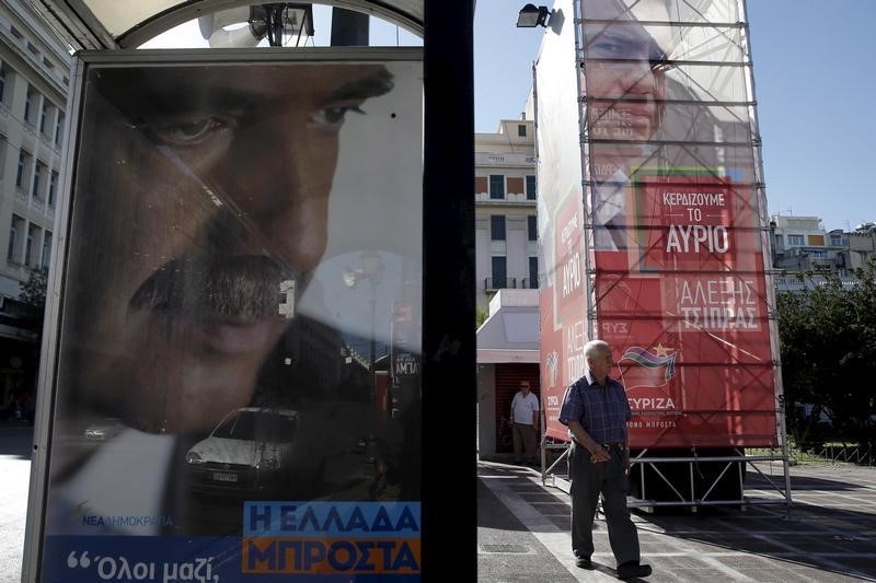 © Reuters. A man walks past pre-election posters with the images of former Greek PM and leader of leftist Syriza party Tsipras and leader of conservative New Democracy party Meimarakis in Athens