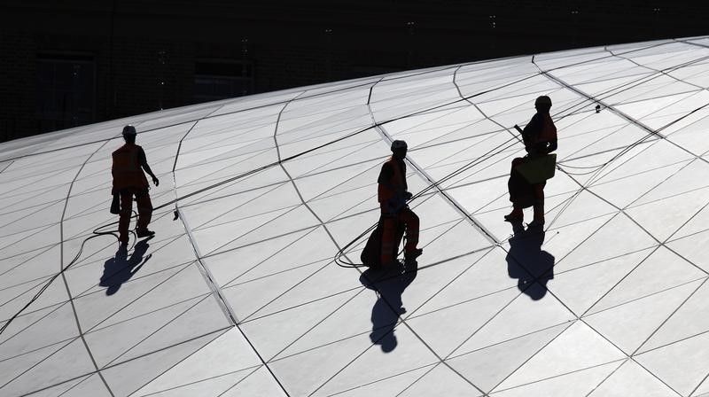 © Reuters. Construction workers fix a roof on a new building at the Kings Cross development in London