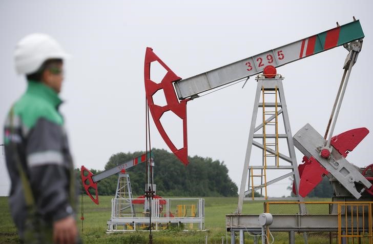 © Reuters. A worker looks at a pump jack at an oil field Buzovyazovskoye owned by Bashneft company north from Ufa