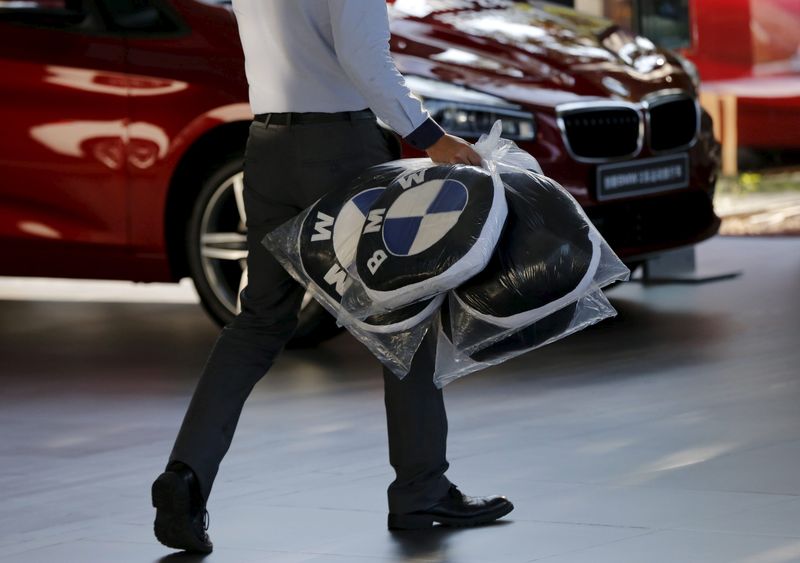 © Reuters. A dealer carries BMW's promotional cushions at a dealer shop in Beijing