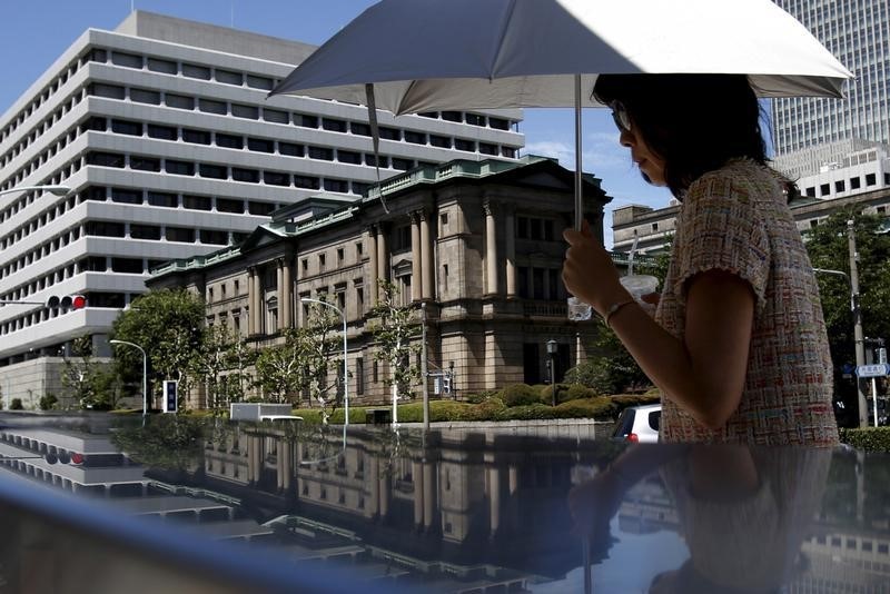 © Reuters. A woman holding an umbrella walks in front of the Bank of Japan headquarters in Tokyo