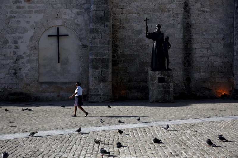 © Reuters. Funcionária caminha diante de estátua de São Francisco de Assis em Havana