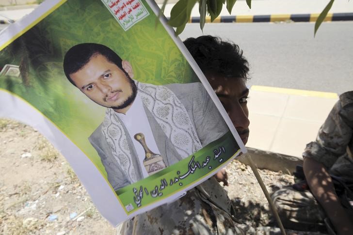 © Reuters. Youth dressed in military uniform holds up a poster of the Houthi movement's leader Abdel-Malek Badruddin al-Houthi while providing security during celebrations marking the 25th anniversary of Yemen's unification, in Sanaa 