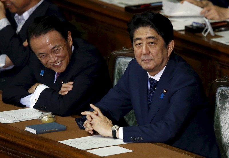 © Reuters. Japan's PM Abe smiles with DPM and Finance Minister Aso during the plenary session for his cabinet's censure motion at at the Lower House of the parliament in Tokyo