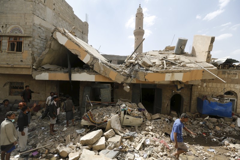 © Reuters. People walk at the site of a Saudi-led air strike in Yemen's capital Sanaa